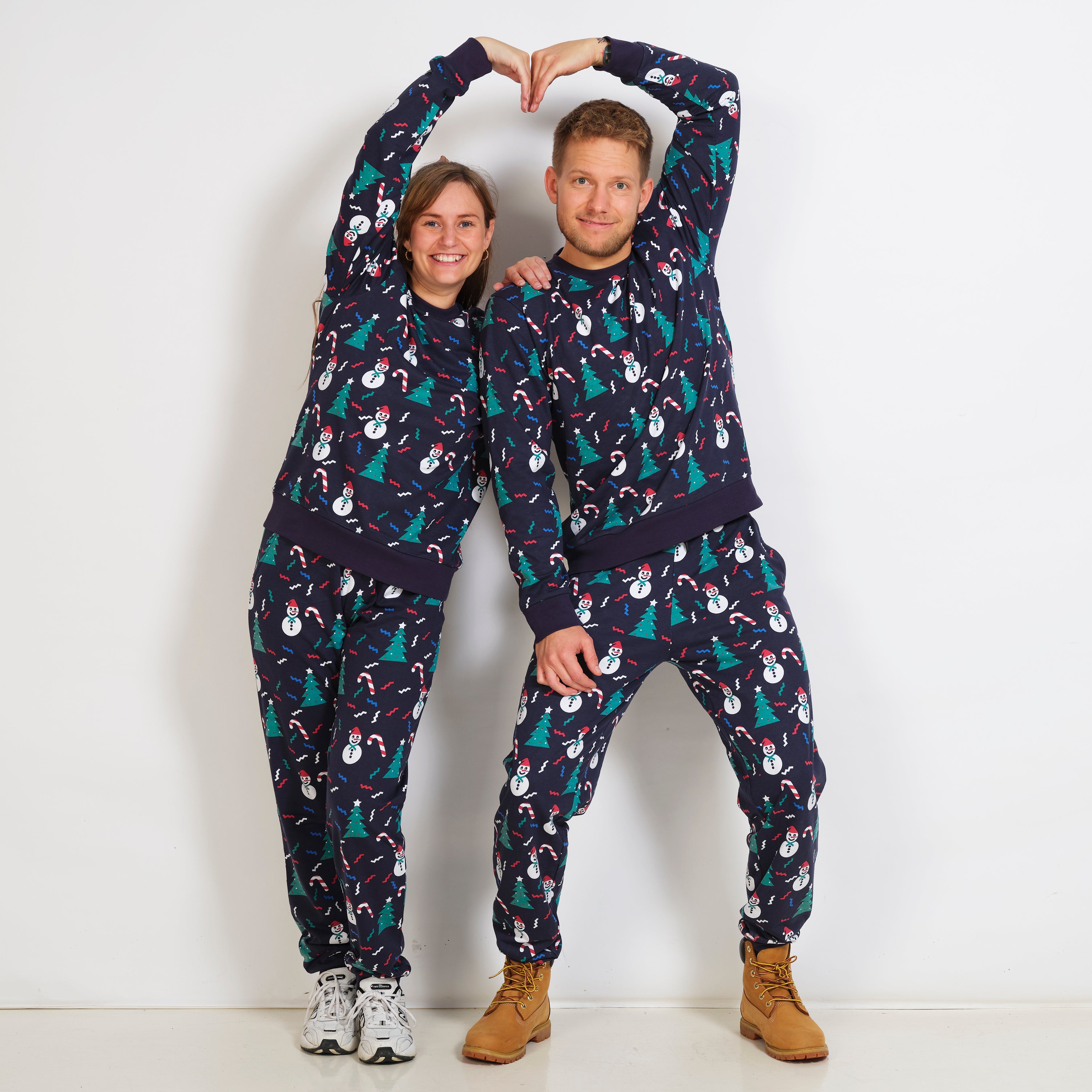 En mann og en kvinne har på seg blå julepyjamas med juletrær på.